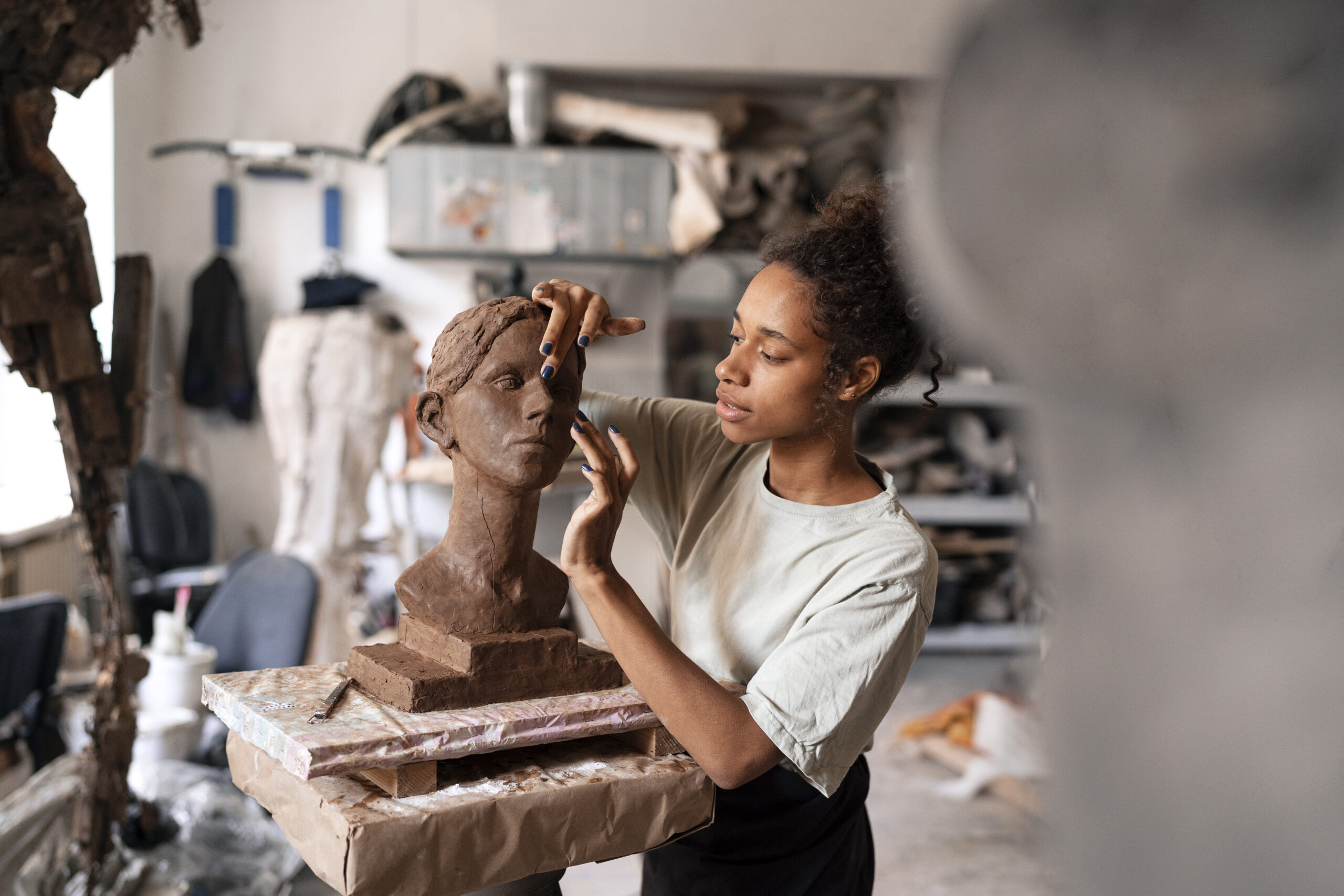 תמונה של אמנית מכינה פסל מחימר כהה